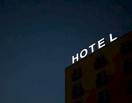 A building with a sign says "HOTEL" against a dark sky, with letters illuminated.