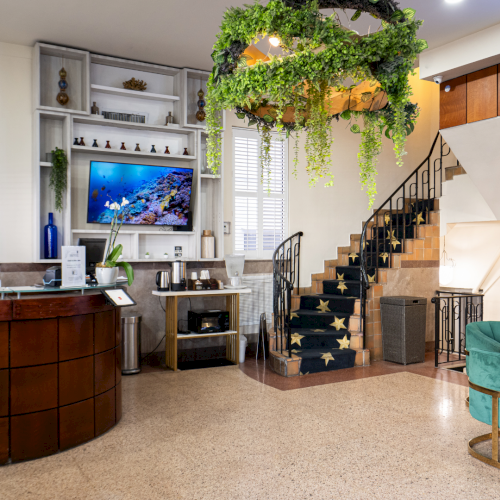 Bright lounge with green vines over a staircase, a cozy fireplace nook, and seating in front of a hookah-themed screen.