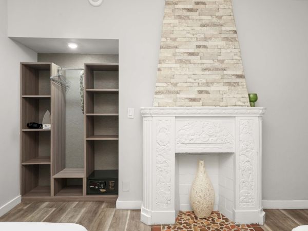A modern living room with a white ornate fireplace, a tall stone chimney, and a built-in open wardrobe/storage nook on the left.